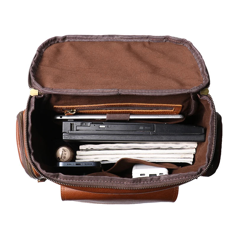 Brown leather briefcase open with various items on a white background