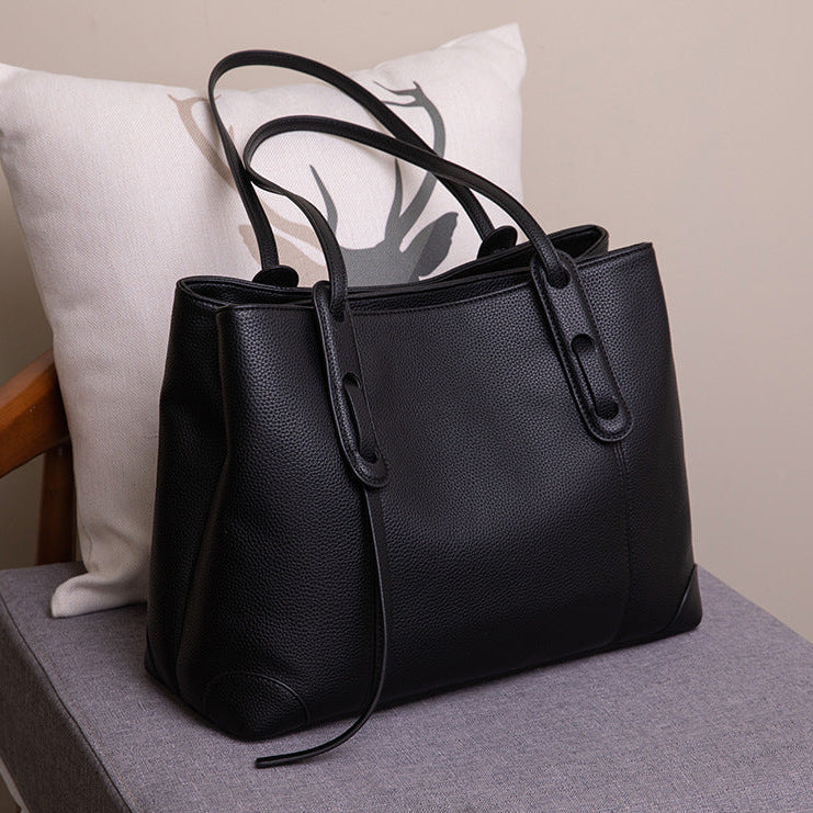Black leather handbag on a chair with a neutral background