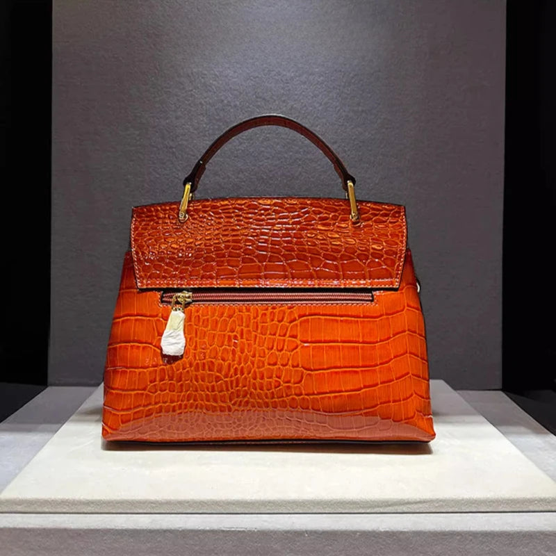 Orange crocodile-patterned handbag on a gray background