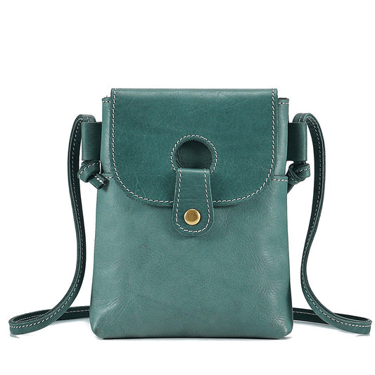 Teal leather crossbody bag with a strap on a white background