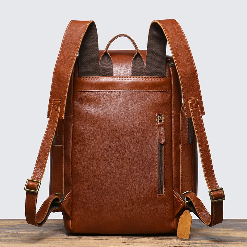 Brown leather backpack on a wooden surface with a light gray background