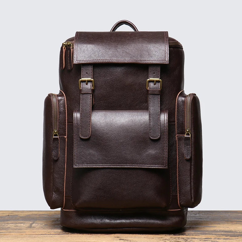 Brown leather backpack on a wooden surface with a light gray background