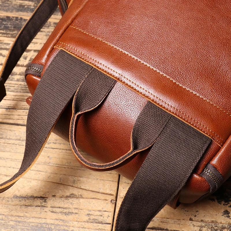 Brown leather bag with a strap on a wooden surface