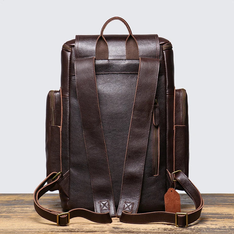 Brown leather backpack on a wooden surface with a light gray background
