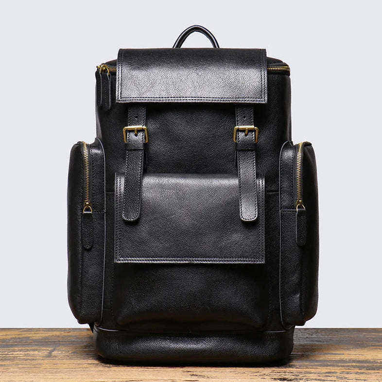 Black leather backpack on a wooden surface with a light gray background