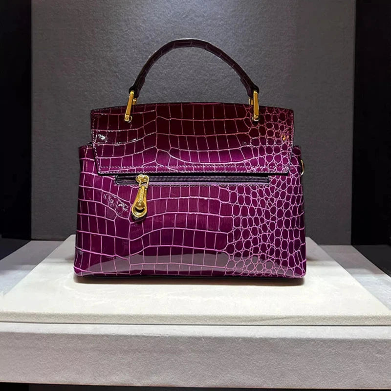 Purple handbag with gold accents on a gray background