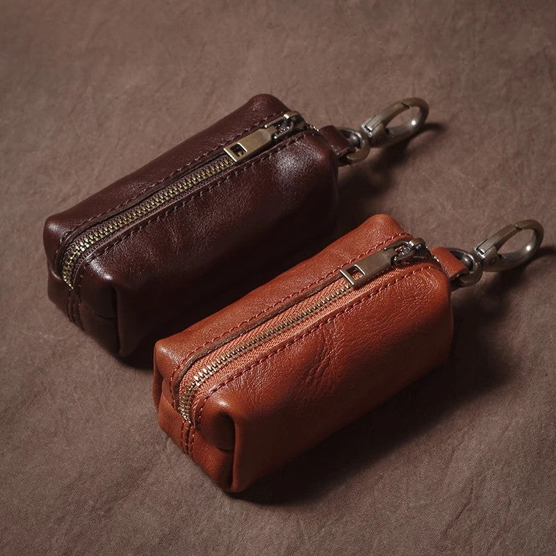 Two brown leather key cases with zippers on a brown background