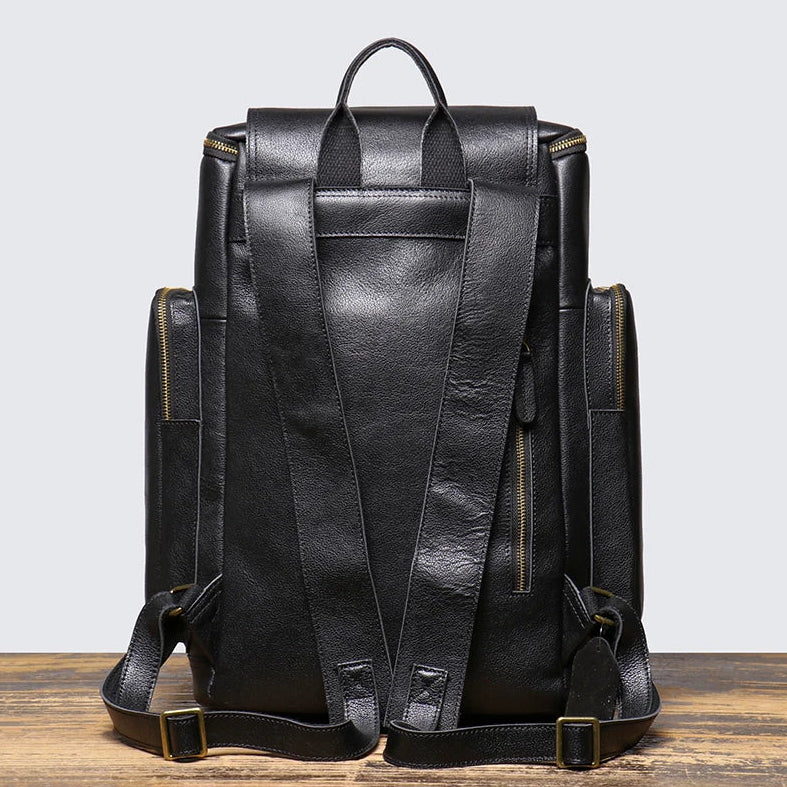Black leather backpack on a wooden surface with a light gray background