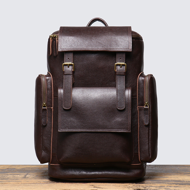 Brown leather backpack on a wooden surface with a light gray background