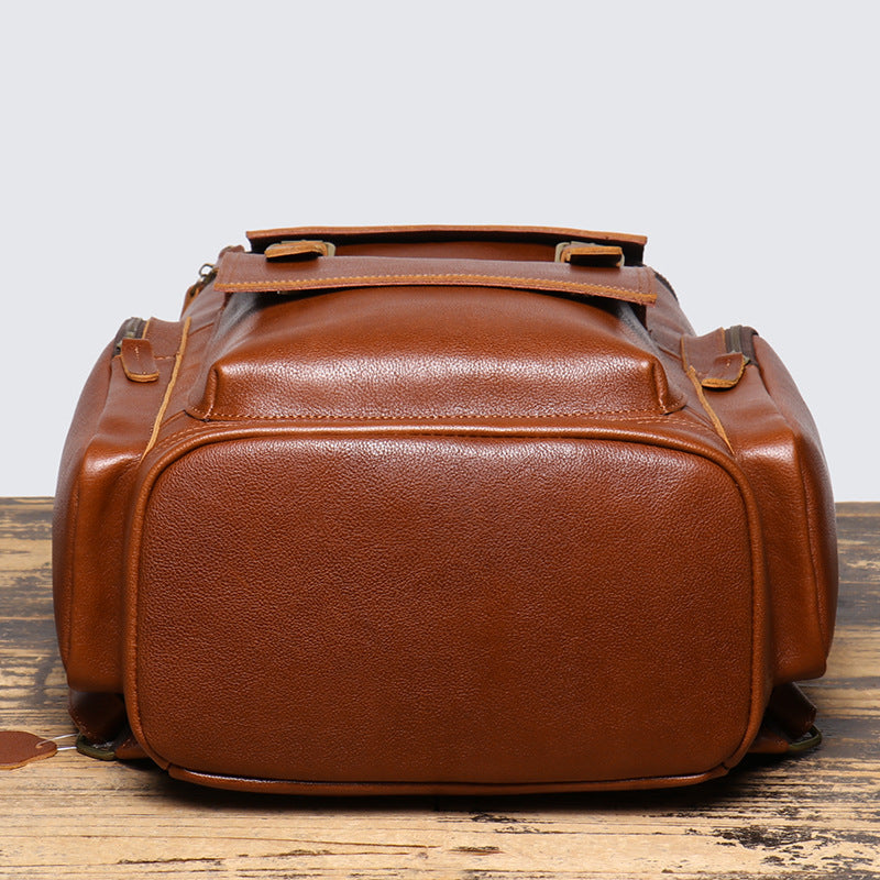 Brown leather duffel bag on a wooden surface with a light gray background