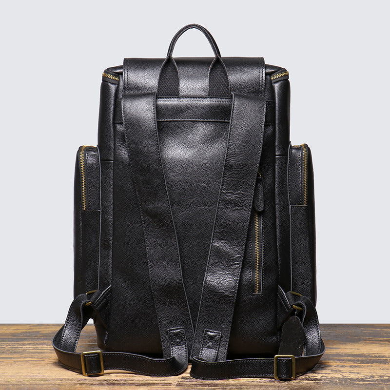 Black leather backpack on a wooden surface with a light gray background