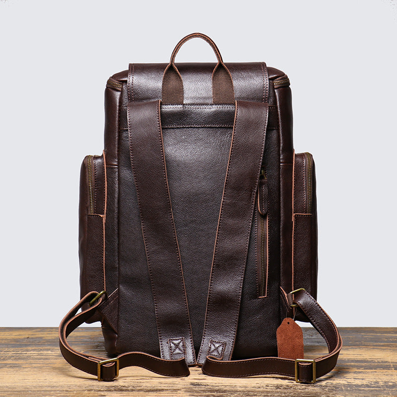 Brown leather backpack on a wooden surface with a light gray background