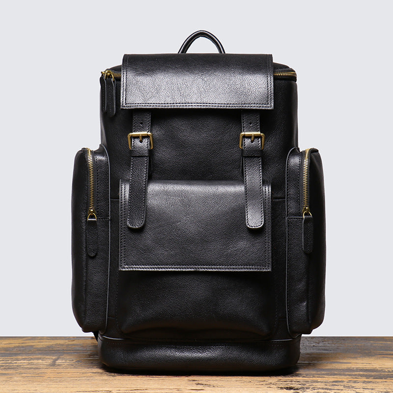Black leather backpack on a wooden surface with a light gray background