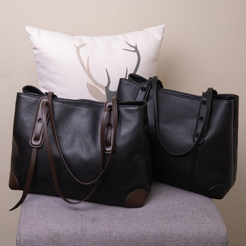 Two black shoulder bags on a gray chair with a beige wall in the background.
