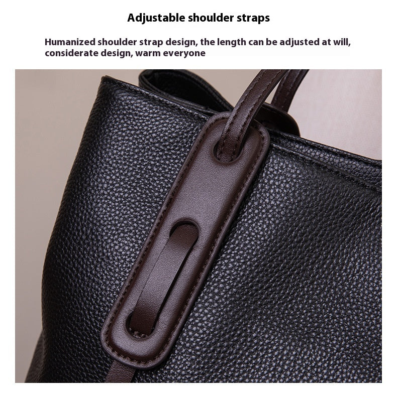 Black leather bag with adjustable brown shoulder strap on a beige background