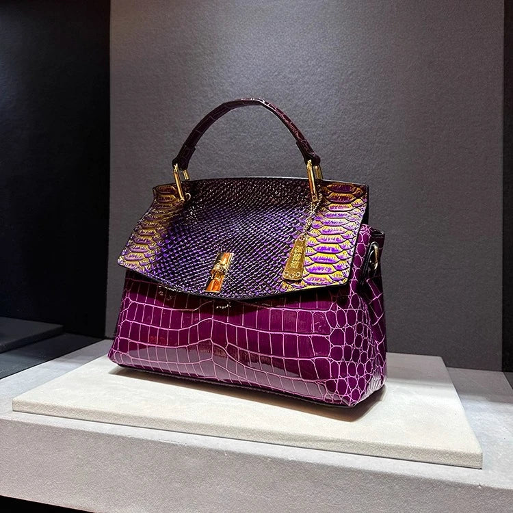 Purple handbag with gold accents on a gray background
