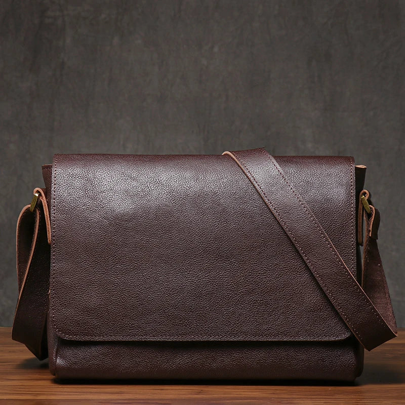Brown leather shoulder bag on a wooden surface with a dark gray background